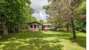 A single-story house with a front porch, surrounded by a well-maintained lawn and trees.