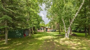A house surrounded by trees with a covered outdoor area and a garage.