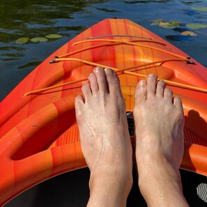 A pair of feet resting on a kayak with a rope tied between them.