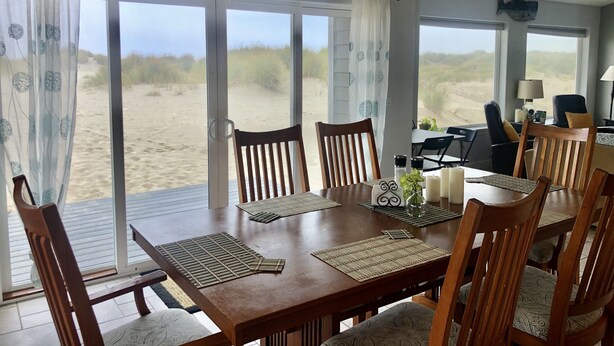 Ein Strandhaus-Interieur mit Essbereich, großen Fenstern und Blick auf den Strand.