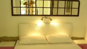 A neatly made bed with white linens and two pillows, a bedside table with a lamp, and a wall-mounted mirror above the bed. - Waldvilla (Kumluca)