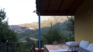 A balcony with a table and chairs, a sofa, and a view of a mountainous landscape. - Waldvilla (Kumluca)