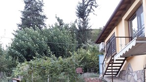 A garden with a stone staircase leading to a building with a yellow facade and a balcony. - Waldvilla (Kumluca)