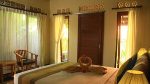 A hotel room with a bed, a wooden chair, a bedside table, and curtains. - Ary House Ubud (Ubud)