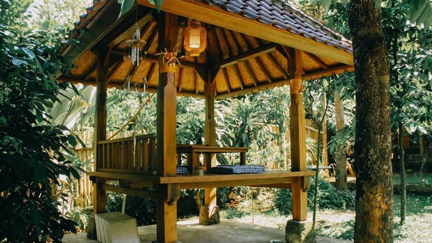 A wooden gazebo with a tiled roof, surrounded by lush greenery. - Ary House Ubud (Ubud)