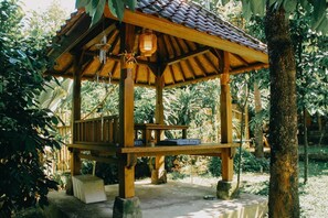 Un gazebo in legno con tetto in tegole, immerso nel verde.