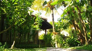 A pathway leading to a traditional thatched-roof structure surrounded by lush greenery. - Ary House Ubud (Ubud)