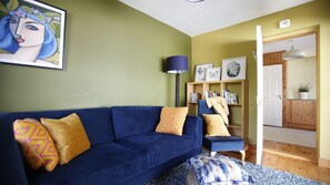 Un salon avec un canapé bleu, une lampe sur pied et une bibliothèque.