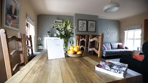 A wooden dining table with a bowl of lemons, a YNA sign, and a magazine. - Dingle Town House 3 bedroom house VRBO (Dingle Peninsula)