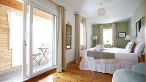 A bedroom with a bed, a chair, a table, and a sliding glass door leading to an outdoor area. - Dingle Town House 3 bedroom house VRBO (Dingle Peninsula)