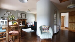 A spacious living room with a wooden chair, a cushioned armchair, and a fireplace. - Dingle Town House 3 bedroom house VRBO (Dingle Peninsula)