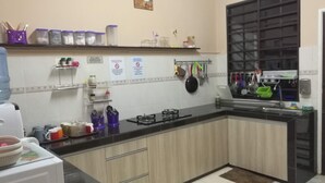 Una cocina con estufa a gas, repisas con recipientes y utensilios colgando en la pared.