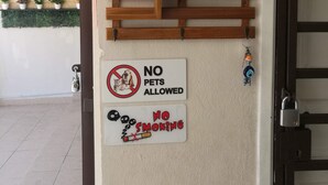 Una pared con un cartel que dice 'No se admiten mascotas', un cartel de 'No fumar' y una ancla decorativa.