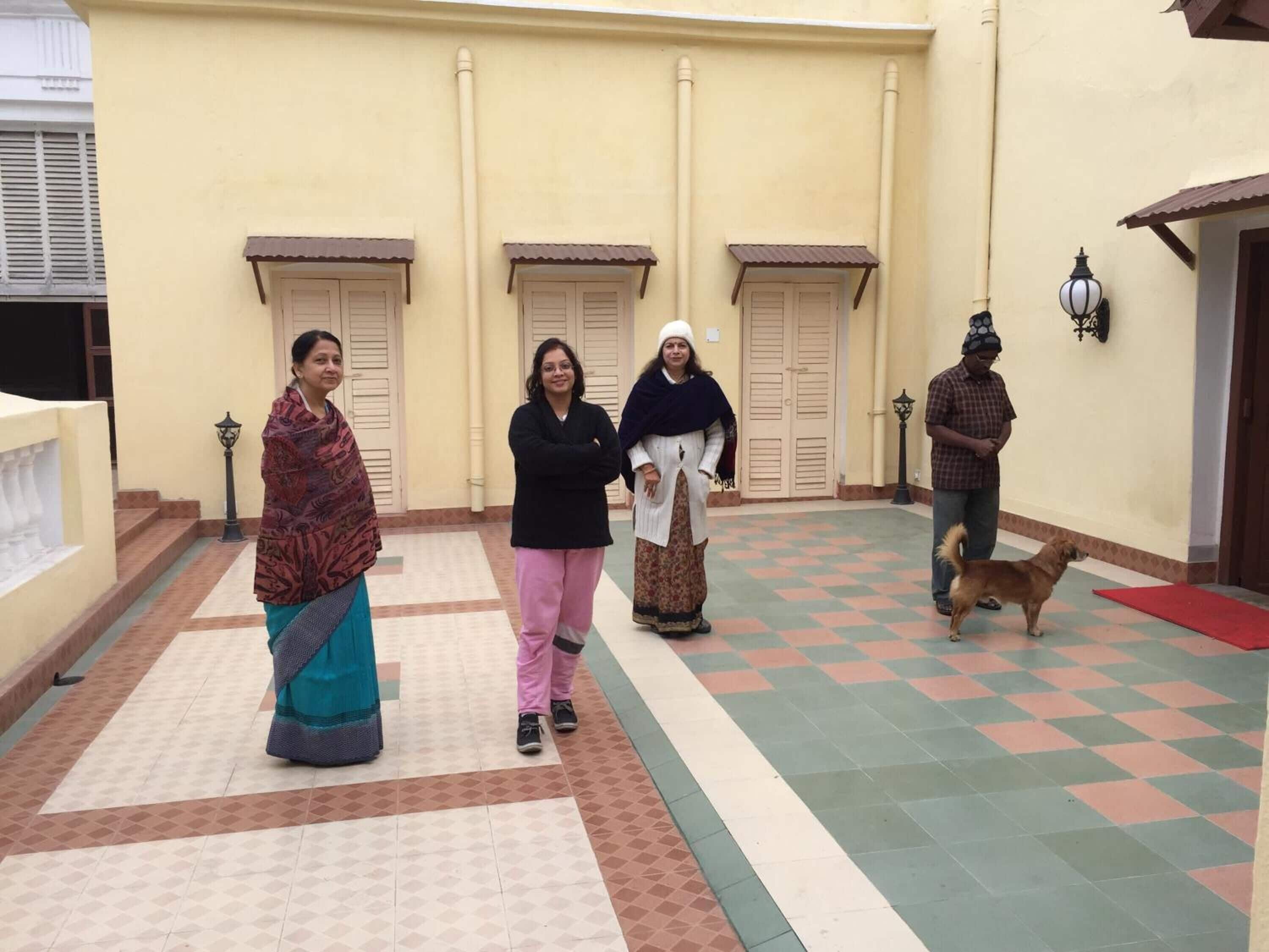 A courtyard with tiled flooring, a dog, and people standing.