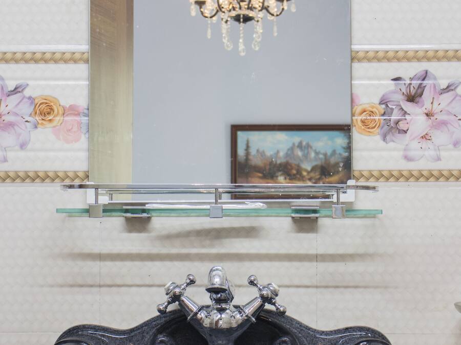 Een badkamer met een zwart wastafel, een glazen plank erboven en een spiegel.