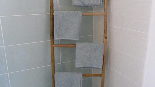 Ein Badezimmer mit einem Bambus-Handtuchhalter, der vier Handtücher trägt.