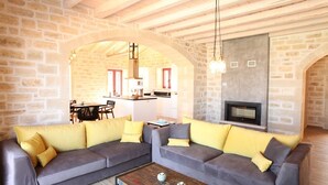 A cozy living room with a grey sectional sofa, a coffee table, and a fireplace. - Villa Dionysos, luxury villa with a fantastic view of a large plot of land (Rethymnon)