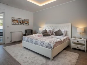 Ein Schlafzimmer mit einem großen Bett, einem Sessel, einem Nachttisch und einer Heizung.