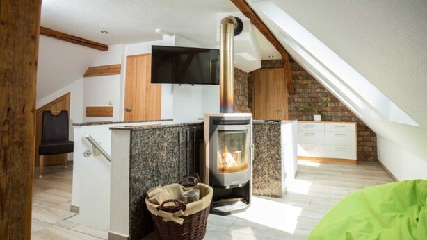 Ein gemütliches Zimmer mit Kamin, Fernseher und Holzbalkendecke.