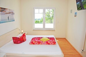 Un dormitorio con cama, ventana y un cuadro colgado en la pared.