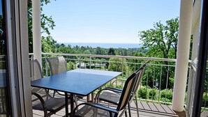 A balcony with a table and chairs, offering a view of the sea and greenery. - Vacation apartment Ostseebad Göhren with great lake view - Ferienwohnung Ostseebad (Göhren)