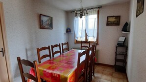 Un coin repas avec une table recouverte d’une nappe colorée, entourée de chaises en bois.