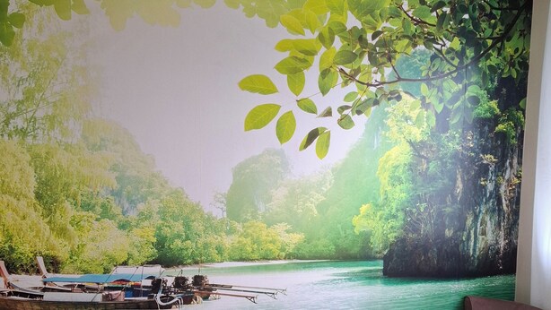 A bedroom with a large mural of a river scene, a bed with a floral bedspread, and a brown armchair. - Close to town center, many shops within walking distance (Revel)