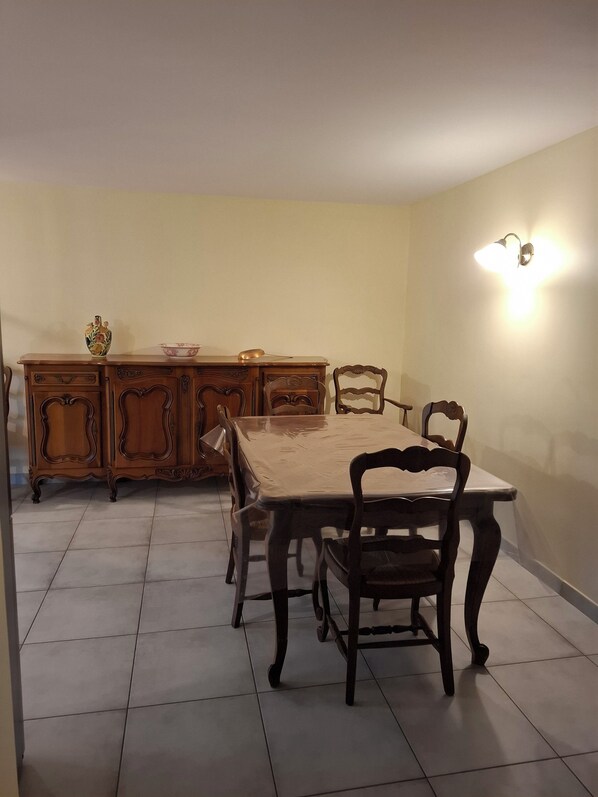 A dining area with a wooden table and chairs, a cabinet, and a wall-mounted light fixture.