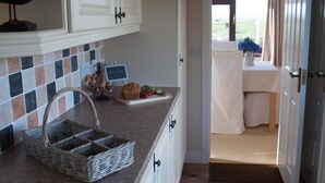 Una cucina con mobili bianchi, una parete rivestita di piastrelle e un cesto sul piano di lavoro.