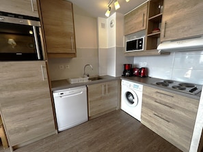 A compact kitchen with a dishwasher, washing machine, microwave, and a stove. - Lovely renovated apartment for 6 in La Croisette (Les Menuires)