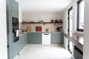 A modern kitchen with teal cabinets, a dishwasher, and a window providing natural light.