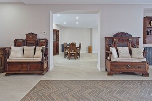 A spacious room with two wooden beds, a dining area, and a hallway leading to another room.