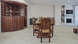 Un comedor con un mueble de madera, un televisor montado en una pared de piedra y una chimenea.