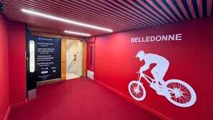 A red carpeted hallway with a wall featuring a cyclist silhouette and the word "BELLEDONNE".