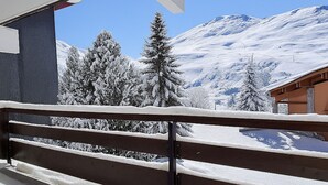 A balcony with a view of snow-covered trees and mountains.