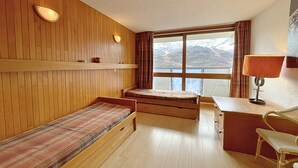 A room with wooden panel walls, a bed, a desk, and a chair.
