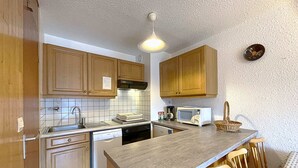 A kitchen with wooden cabinets, a microwave, a sink, and a dishwasher.