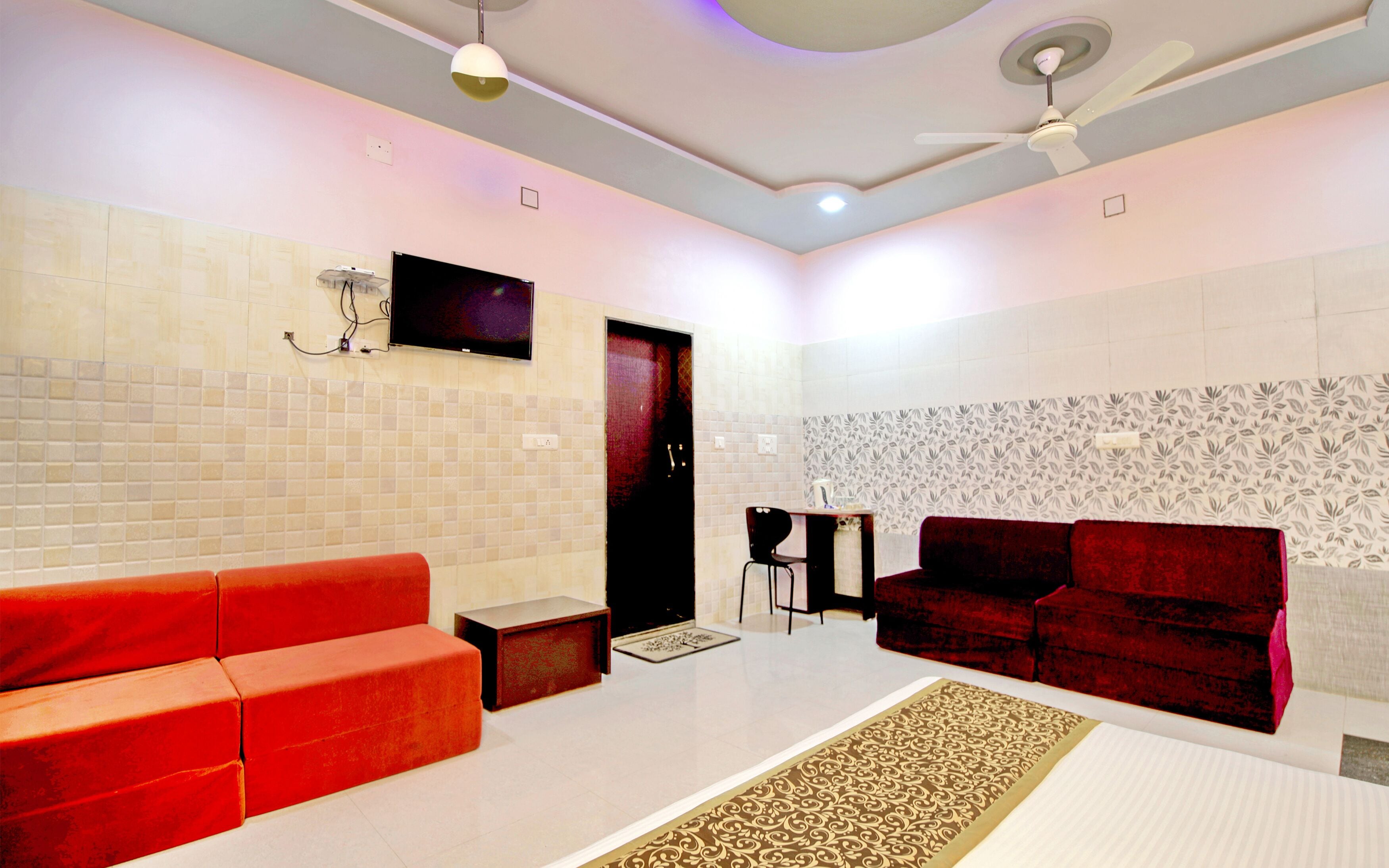 A modern living room with a red sofa, a black chair, and a patterned rug.