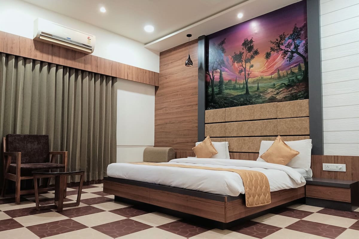 Una habitación de hotel moderna con una cama grande, una silla, un cuadro en la pared y un suelo a cuadros.