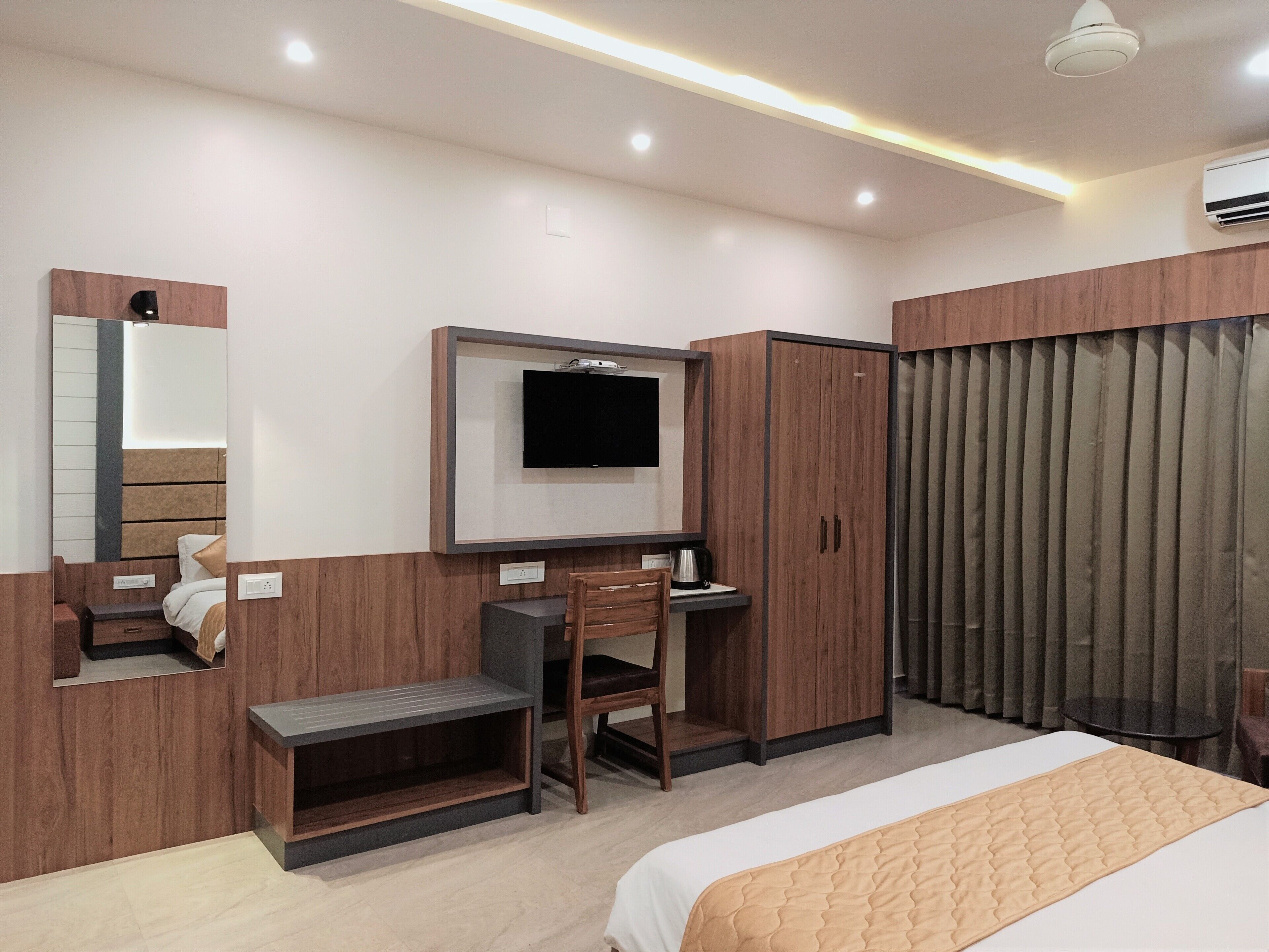Ein modernes Hotelzimmer mit Bett, Schreibtisch, Sessel, Fernseher und Kleiderschrank.