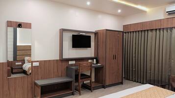 A modern hotel room with a bed, a desk, a chair, a television, and a wardrobe.