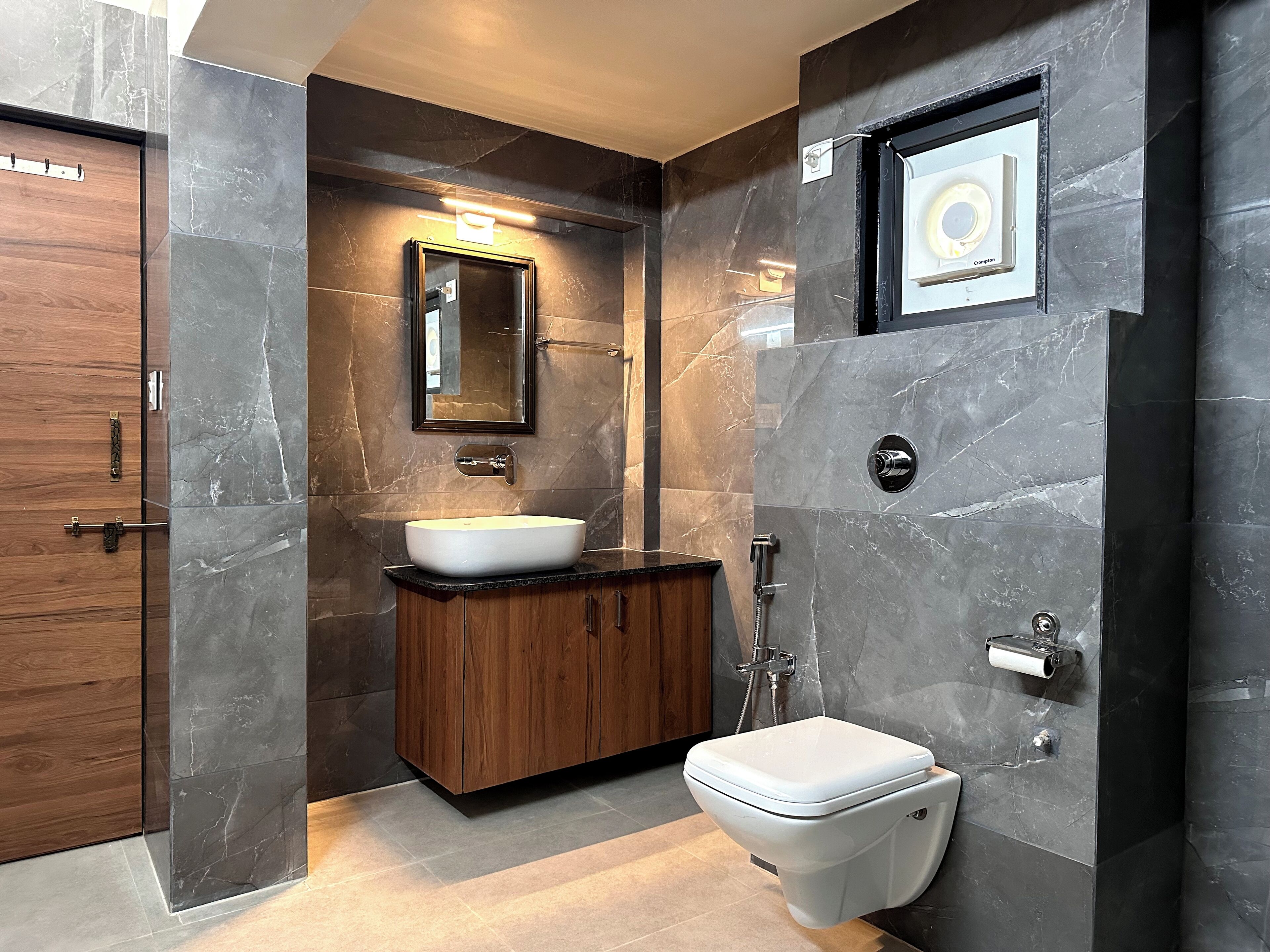 A modern bathroom with a marble sink, wooden vanity, and a toilet.