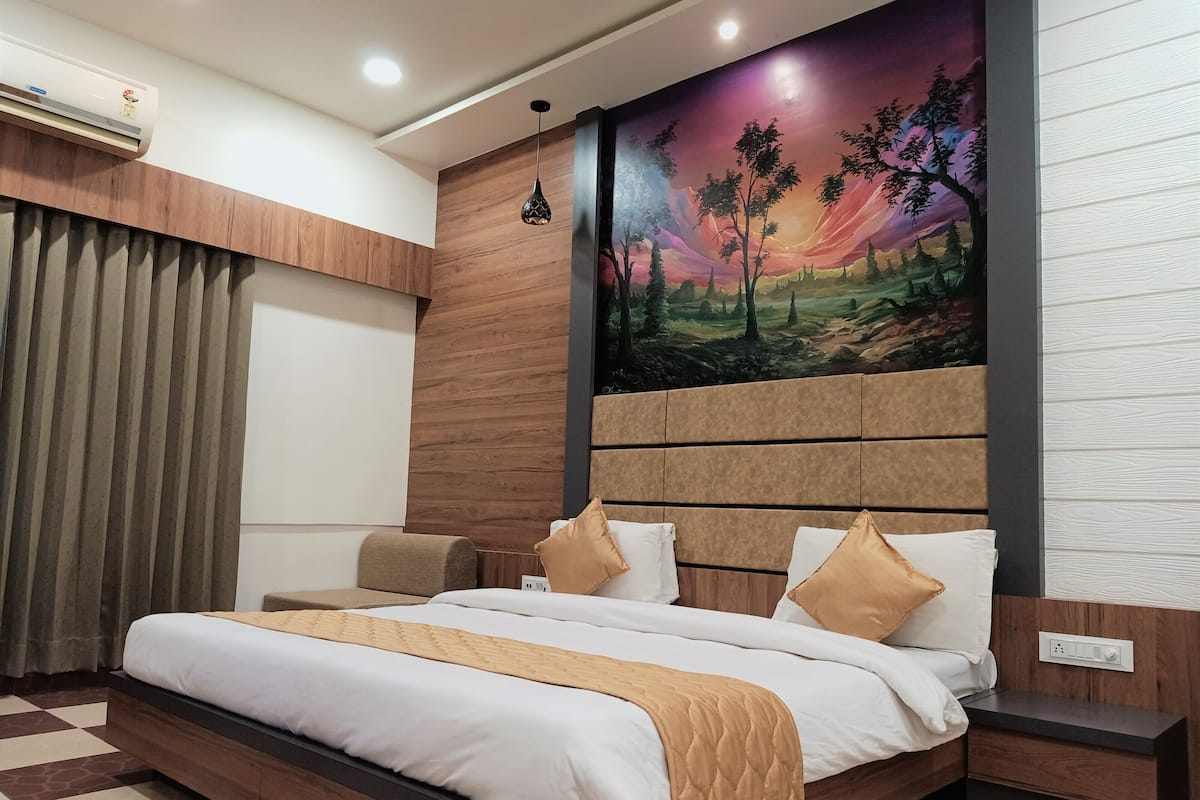 Un dormitorio moderno con una cama grande, cabecera con un mural, mesita de noche y aire acondicionado instalado en la pared.