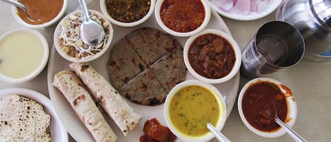 A variety of dishes and condiments on a table, including flatbreads, soups, and a plate with sliced onions and lime.