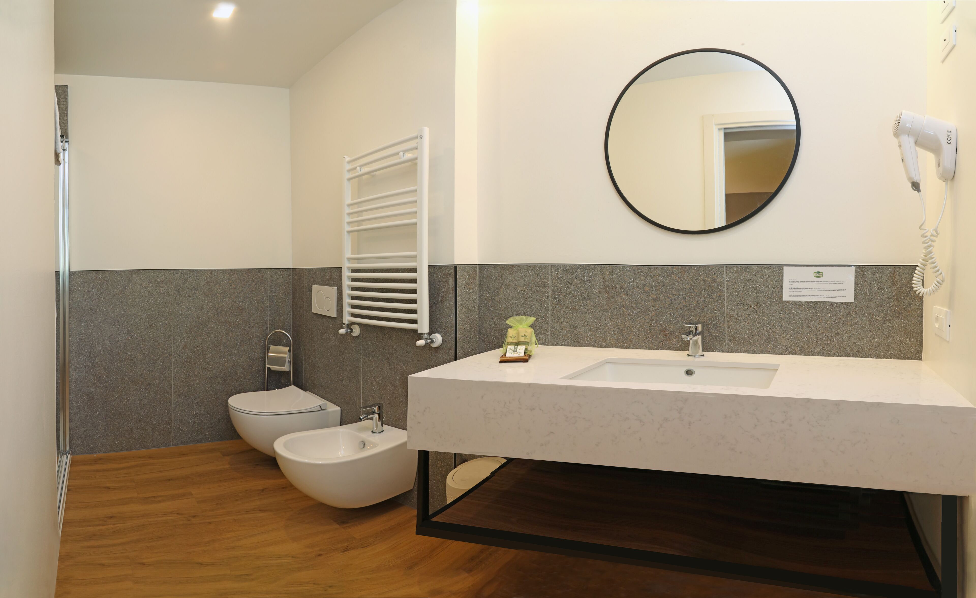 A modern bathroom with a bidet, a sink, a mirror, and a towel rack.