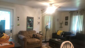 A living room with a brown sofa, a black sofa, a white chair, a coffee table, and a patterned rug.