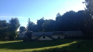 A large, open grassy field with a small, single-story building in the center.