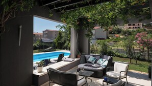 Une terrasse extérieure avec une piscine, un espace salon et des plantes en pot.