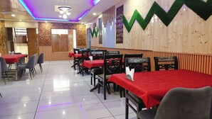 Un restaurant avec de nombreuses tables recouvertes de nappes rouges, disposées en rangées.