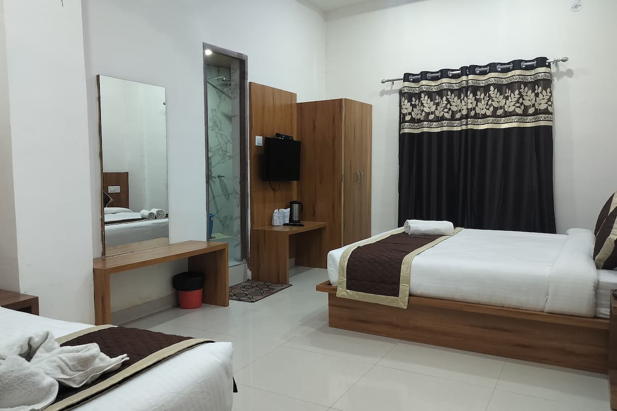 A hotel room with two beds, a wooden wardrobe, a mirror, a television, and a shower area.
